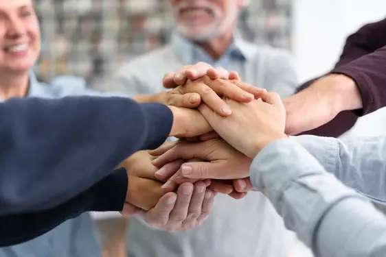 Image en gros plan d'un groupe de mains diverses empilées les unes sur les autres dans un geste de travail d'équipe, d'unité et de collaboration.